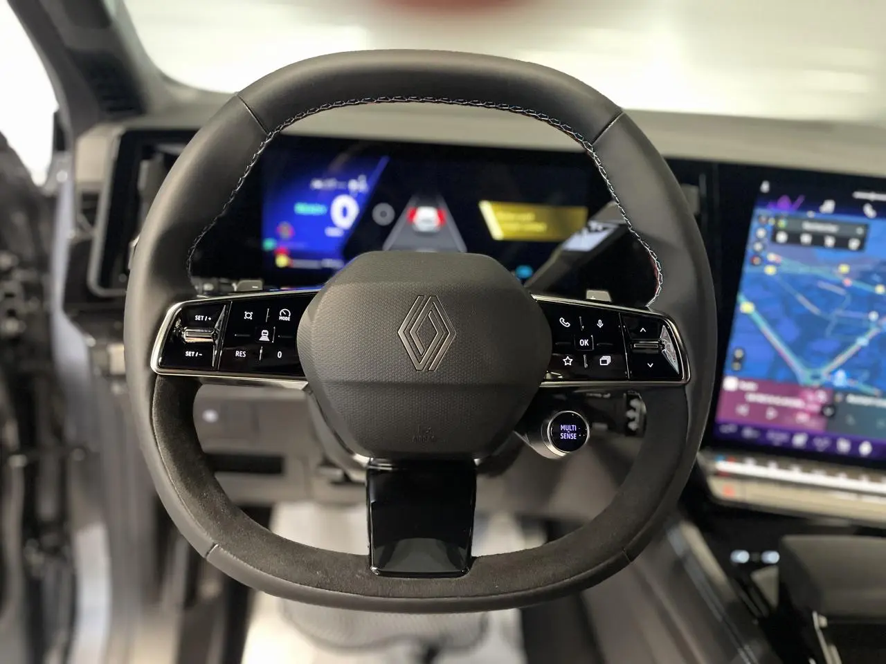 Vue rapprochée du volant multifonction en cuir et alcantara du Renault Austral 2025 avec tableau de bord numérique et écran tactile.