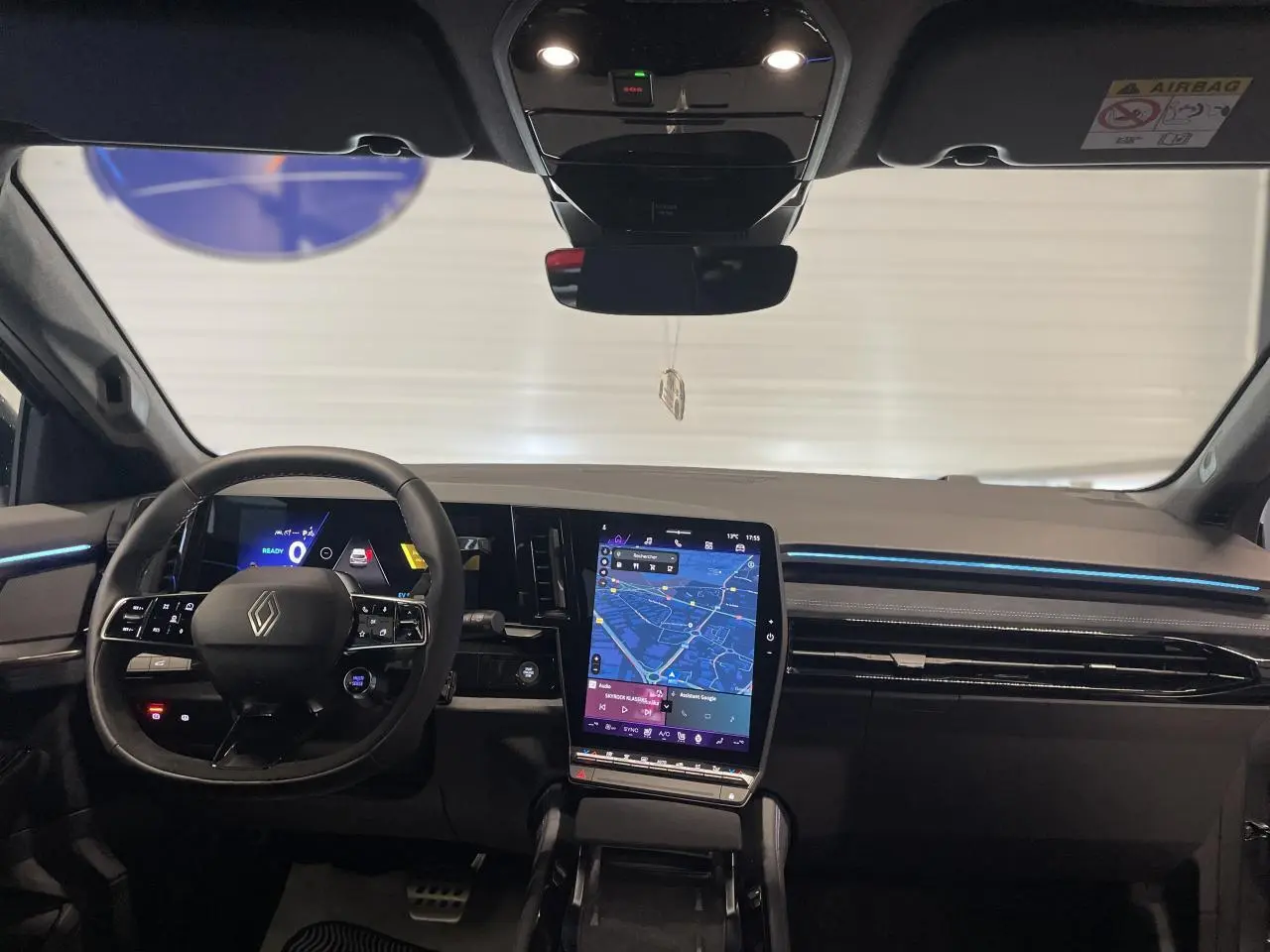Vue intérieure du tableau de bord du Renault Austral 2025 avec écran tactile vertical et éclairage d'ambiance bleu.