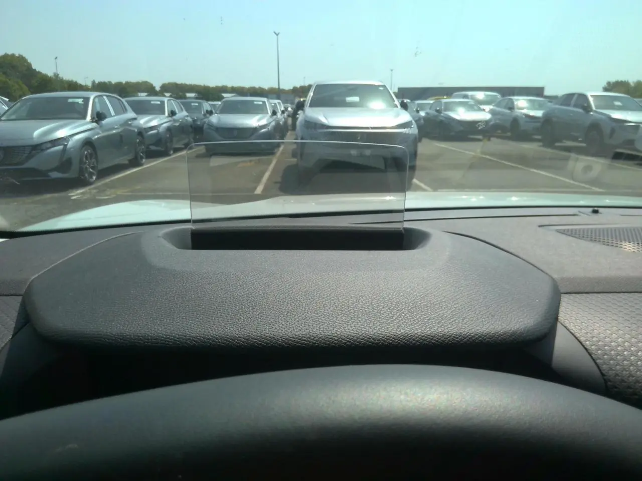 Vue depuis l'intérieur d'une Citroën C4 Hybrid blanche, avec affichage tête haute et tableau de bord noir texturé.