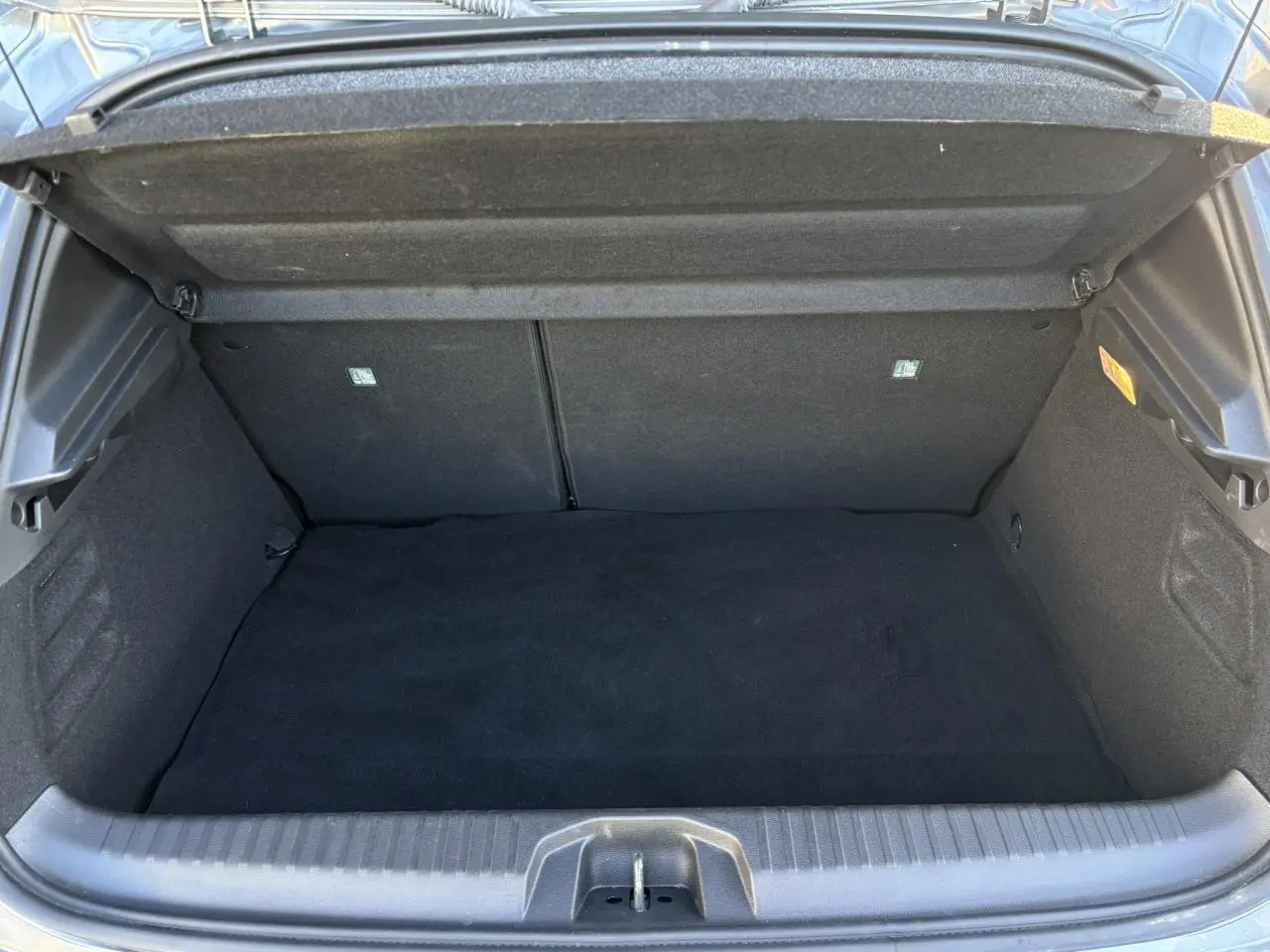 Coffre ouvert vu de face de la Renault Clio V E-Tech Full Hybrid 145 Techno gris Schiste, intérieur noir.