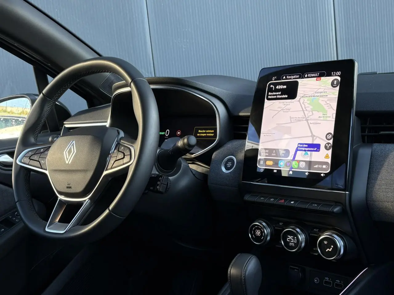 Vue intérieure côté conducteur de la Renault Clio V E-Tech 145 Techno, avec volant multifonction et écran tactile 9,3 pouces.