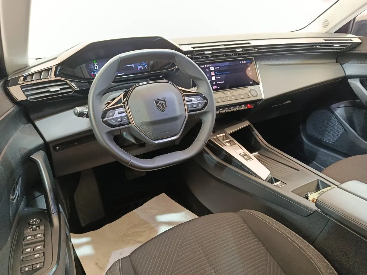 Vue intérieure du poste de conduite de la Peugeot 308 2022, volant cuir multifonctions et écran tactile central.