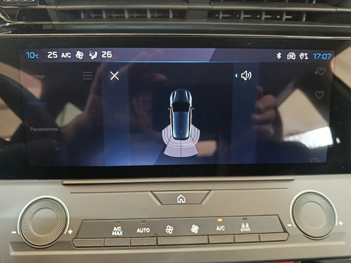 Écran tactile central de la Peugeot 308 blanc, affichant l'aide au stationnement vue de dessus.