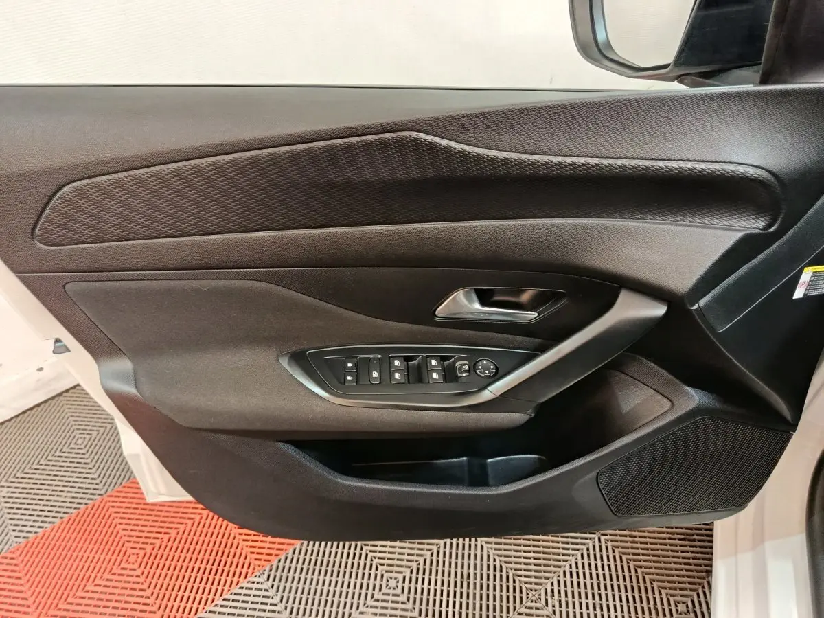 Vue rapprochée de la porte avant gauche noire de la Peugeot 308 blanche avec commandes électriques des vitres et rétroviseurs.