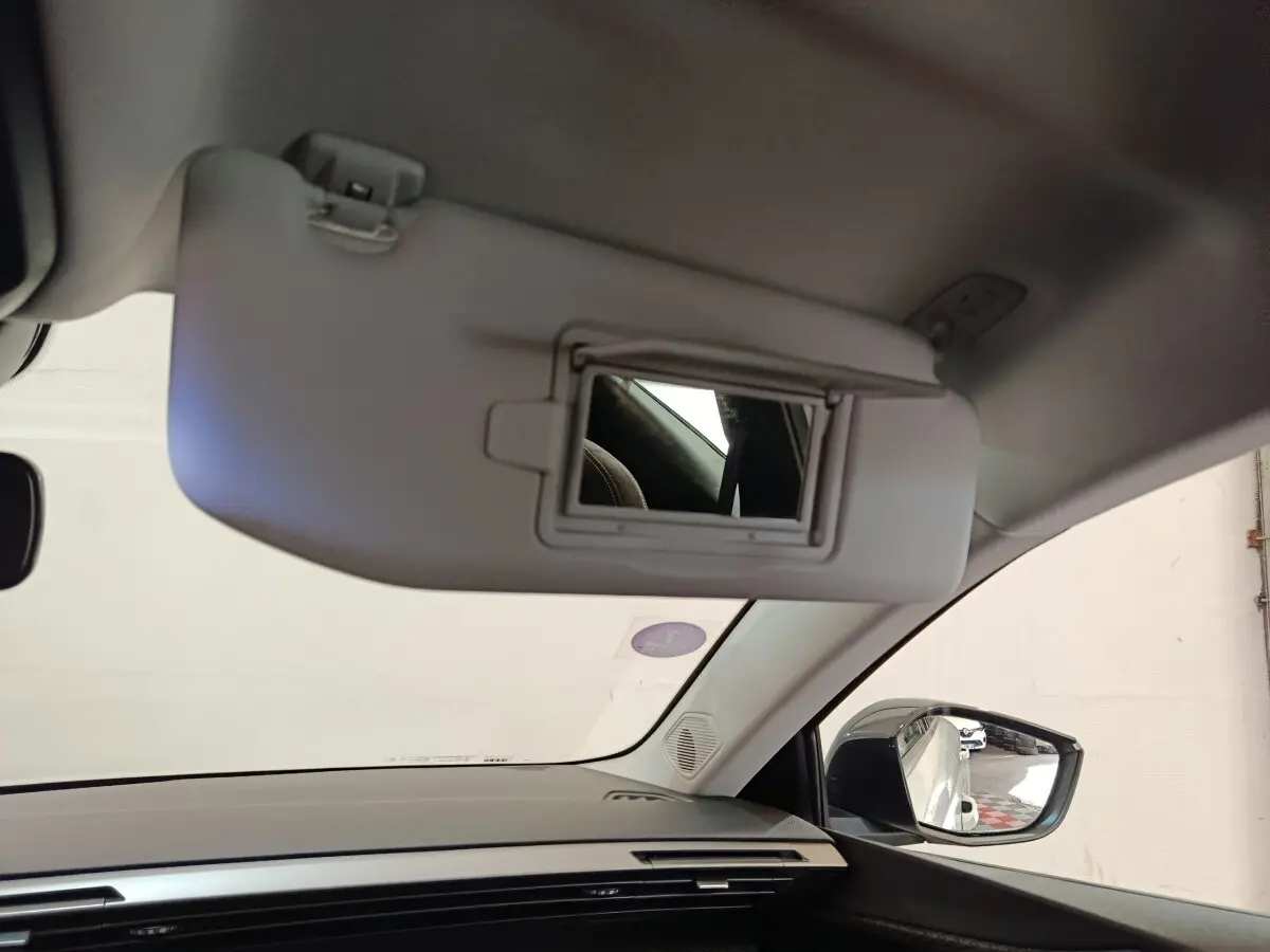 Détail intérieur du pare-soleil avec miroir ouvert côté conducteur d'une Peugeot 308 blanche, vue du siège avant.