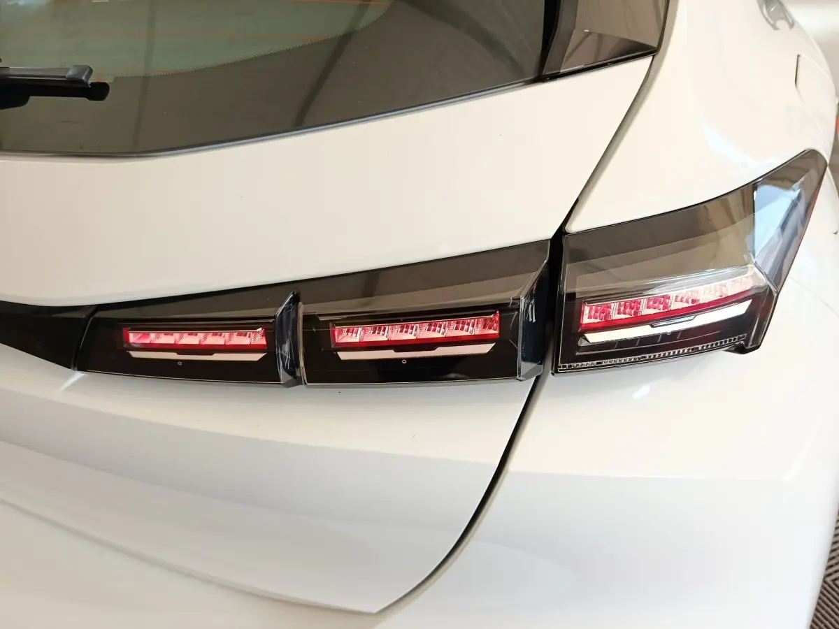 Gros plan sur les feux arrière rouges et noirs d'une Peugeot 308 blanche vue de l'arrière droit.