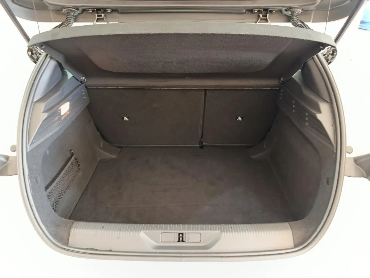 Coffre ouvert vu de l'arrière d'une Peugeot 308 blanche, montrant un espace de chargement propre et spacieux.