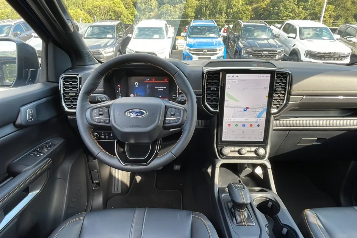 Vue intérieure frontale du Ford Ranger 2025 avec volant cuir, écran tactile vertical et sellerie noire.