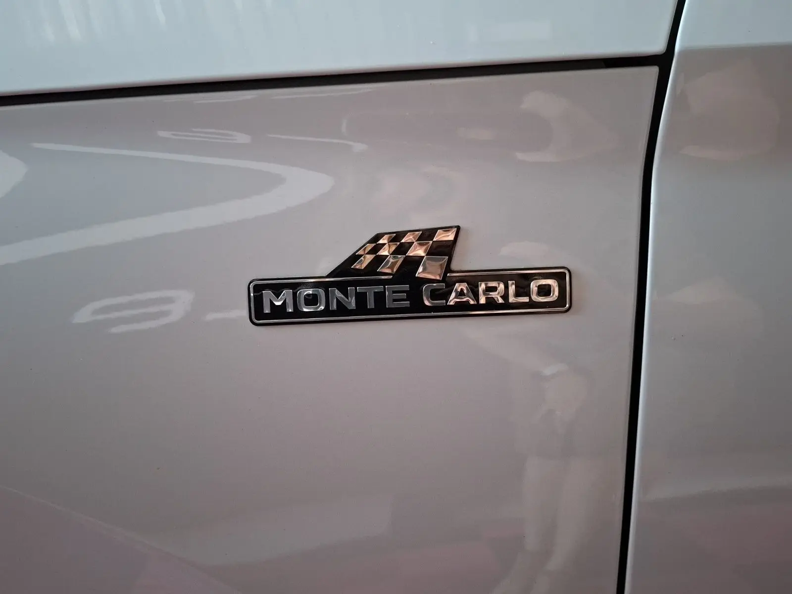 Gros plan sur l’écusson Monte Carlo noir et argent sur la portière blanche d’un Skoda Kamiq 2021.