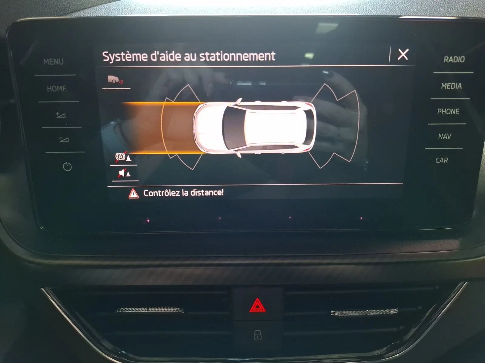 Écran central du Skoda Kamiq blanc montrant l'aide au stationnement avec alertes de distance active.
