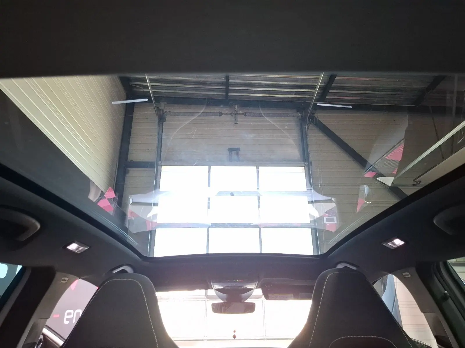 Vue intérieure du toit panoramique du Skoda Kamiq blanc 2021, mettant en valeur l'espace lumineux au-dessus des sièges avant.