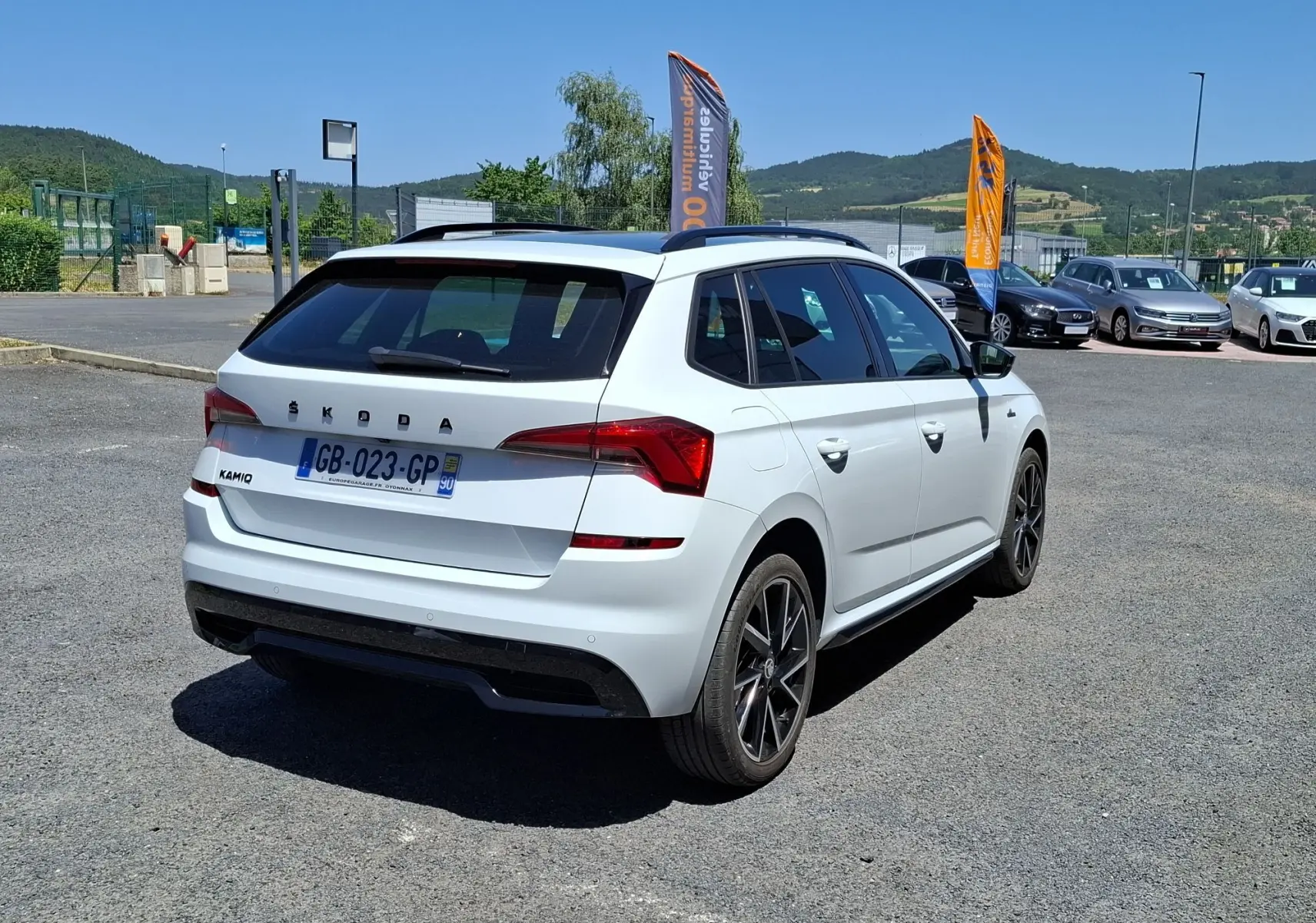 Vue 3/4 arrière droite d'un Skoda Kamiq blanc avec jantes alliage noires et vitres arrière surteintées.