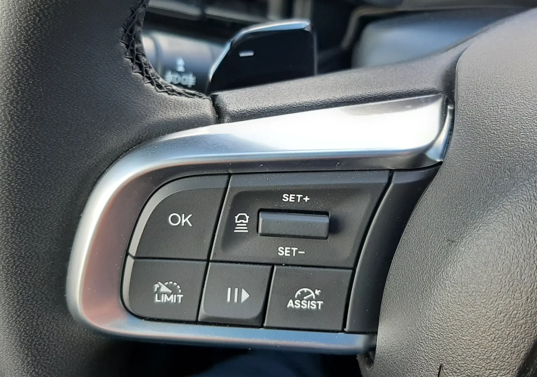 Gros plan sur les commandes au volant côté gauche d'une Fiat 600 1.2 Hybrid 2025 avec tableau de bord vert sky.