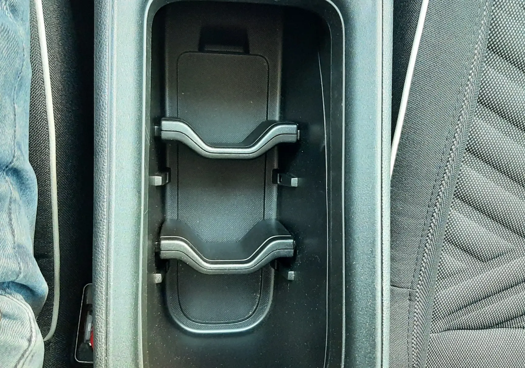 Gros plan sur le porte-gobelets central noir entre les sièges avant gris foncé d'une FIAT 600 2025.