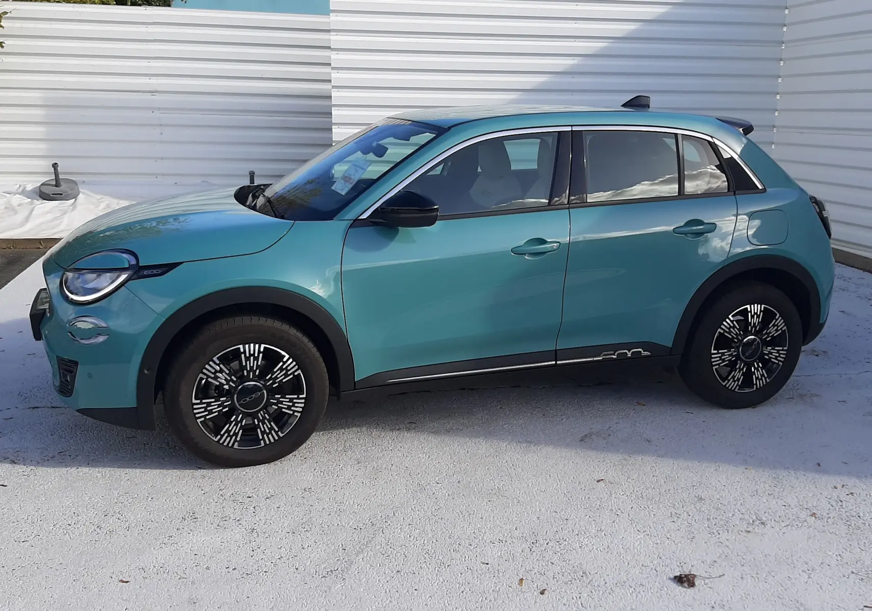 Vue de profil côté gauche d'une FIAT 600 1.2 Hybrid 2025 en vert Sky avec jantes noires à motifs blancs.