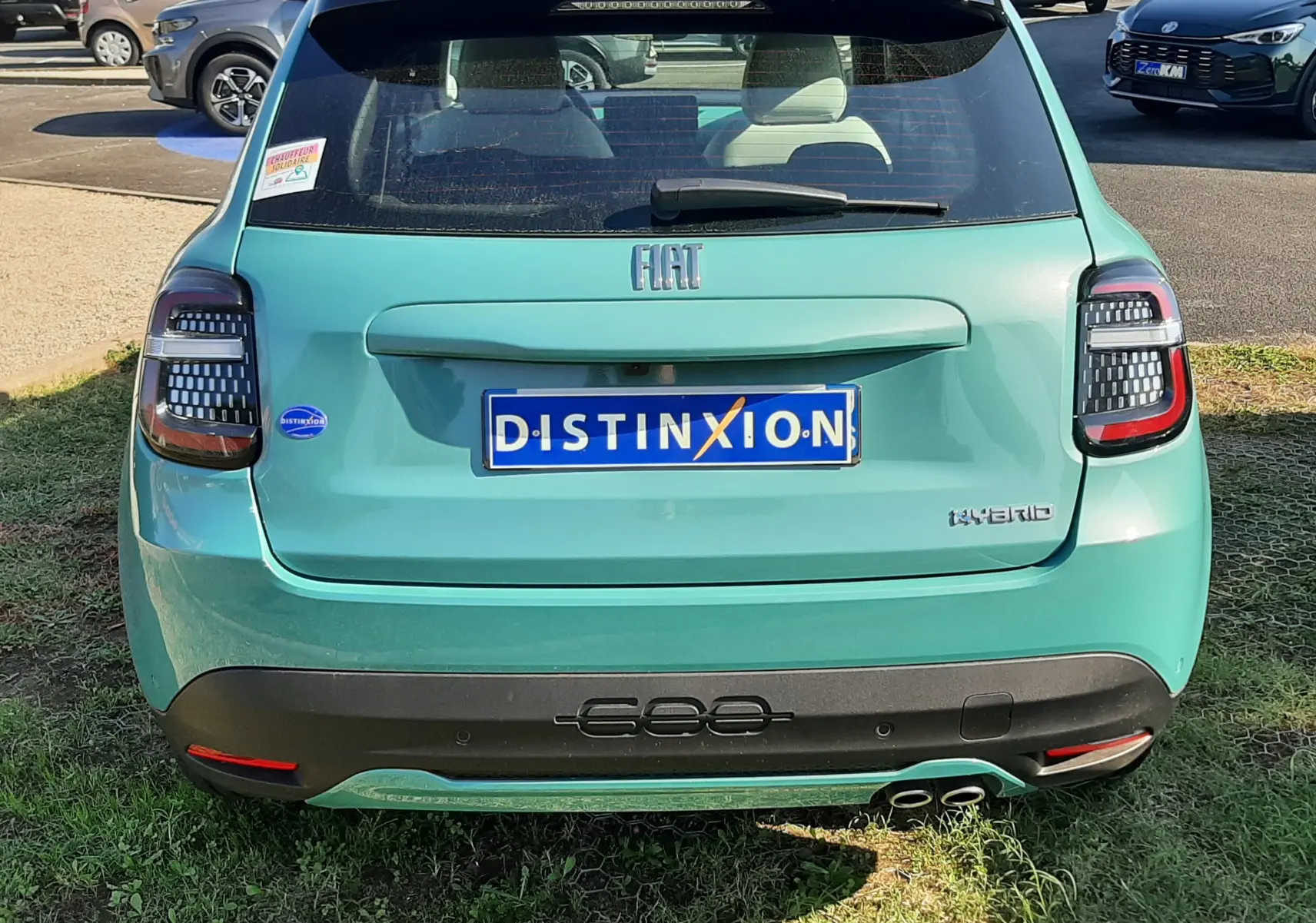 Vue de côté droit arrière d'une FIAT 600 1.2 Hybrid 2025 en vert sky avec jantes noires à motifs blancs et toit noir.
