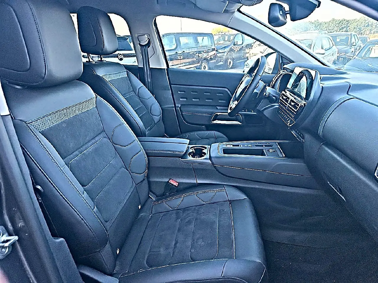 Intérieur avant du Citroën C5 Aircross 2024 gris platinium, vue côté gauche avec sièges cuir noirs et tableau de bord moderne.