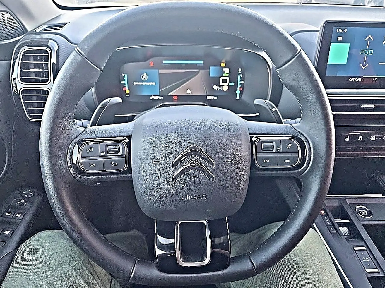Vue frontale du volant cuir noir et du tableau de bord numérique du Citroën C5 Aircross hybride 2024.