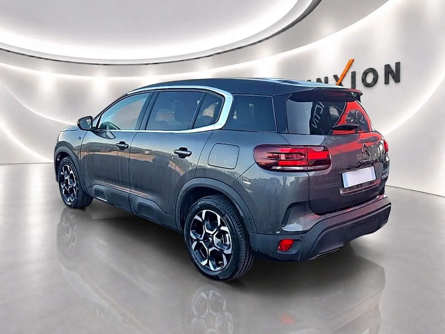 Citroën C5 Aircross gris platinium vue 3/4 arrière droit avec jantes alu et vitres teintées dans showroom.