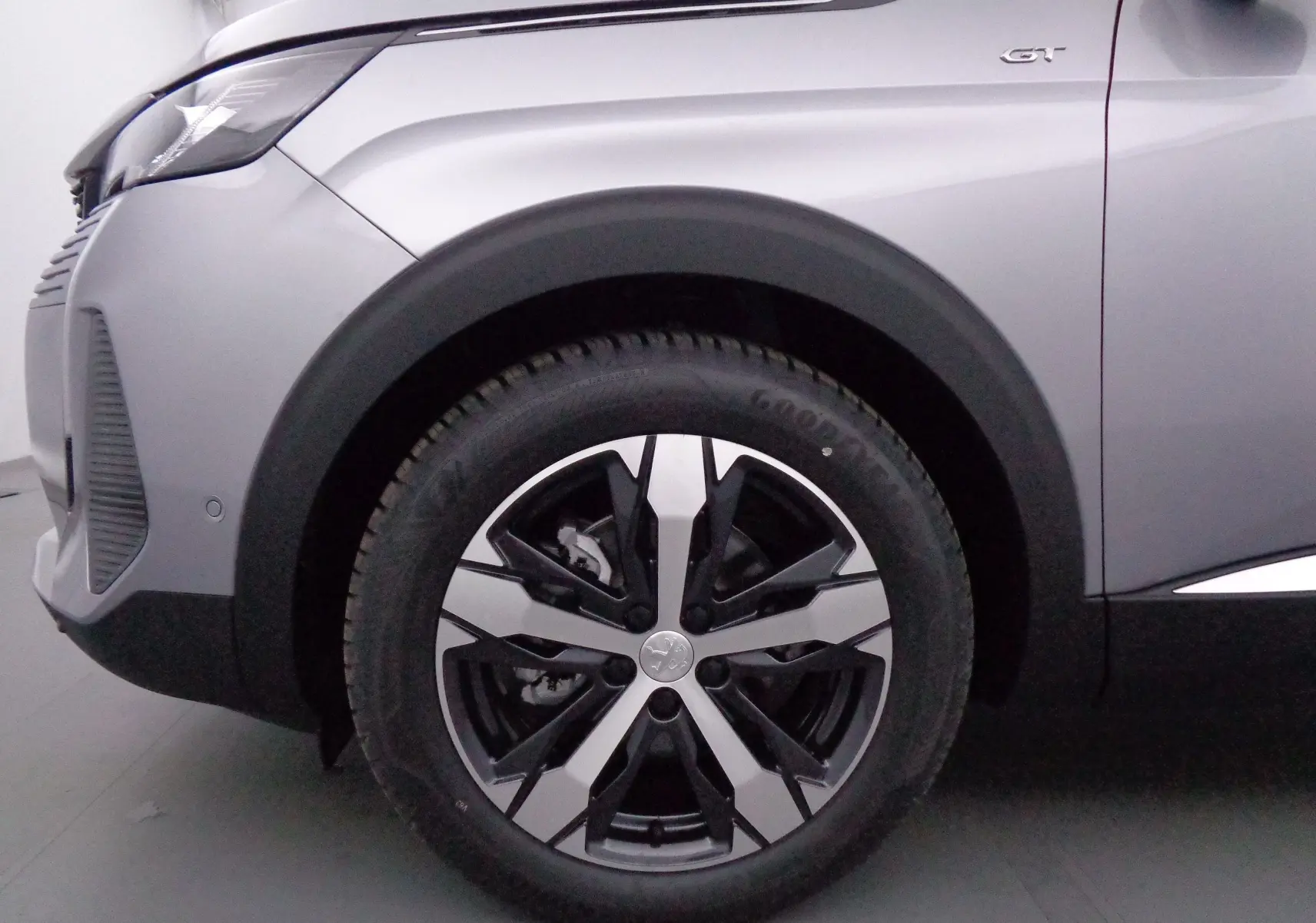 Gros plan sur la roue avant gauche et l'aile gris Artense métallisé du Peugeot 3008 GT 2023 avec logo GT visible.