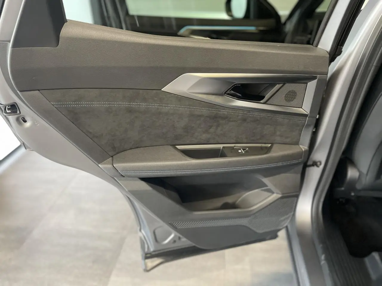Gros plan sur la porte arrière gauche du Renault Austral gris satin mat avec insert Alcantara et surpiqûres blanches.