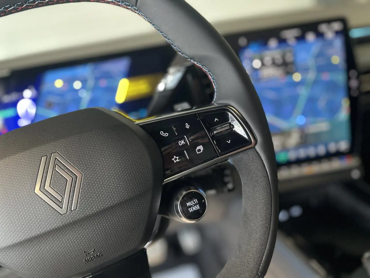 Gros plan sur le volant Alcantara avec surpiqûres tricolores et commandes multifonctions du Renault Austral Esprit Alpine.