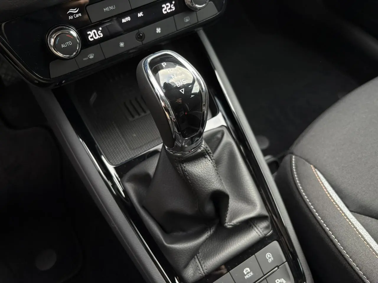 Gros plan sur la console centrale du Skoda Kamiq gris argent, mettant en valeur le levier de vitesses automatique et les commandes environnantes.