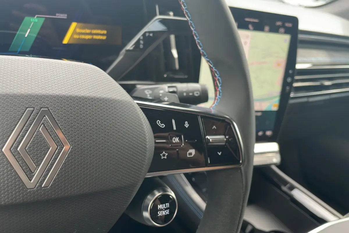 Gros plan sur le volant multifonctions du Renault Austral gris schiste avec commandes et bouton Multi Sense, intérieur moderne.