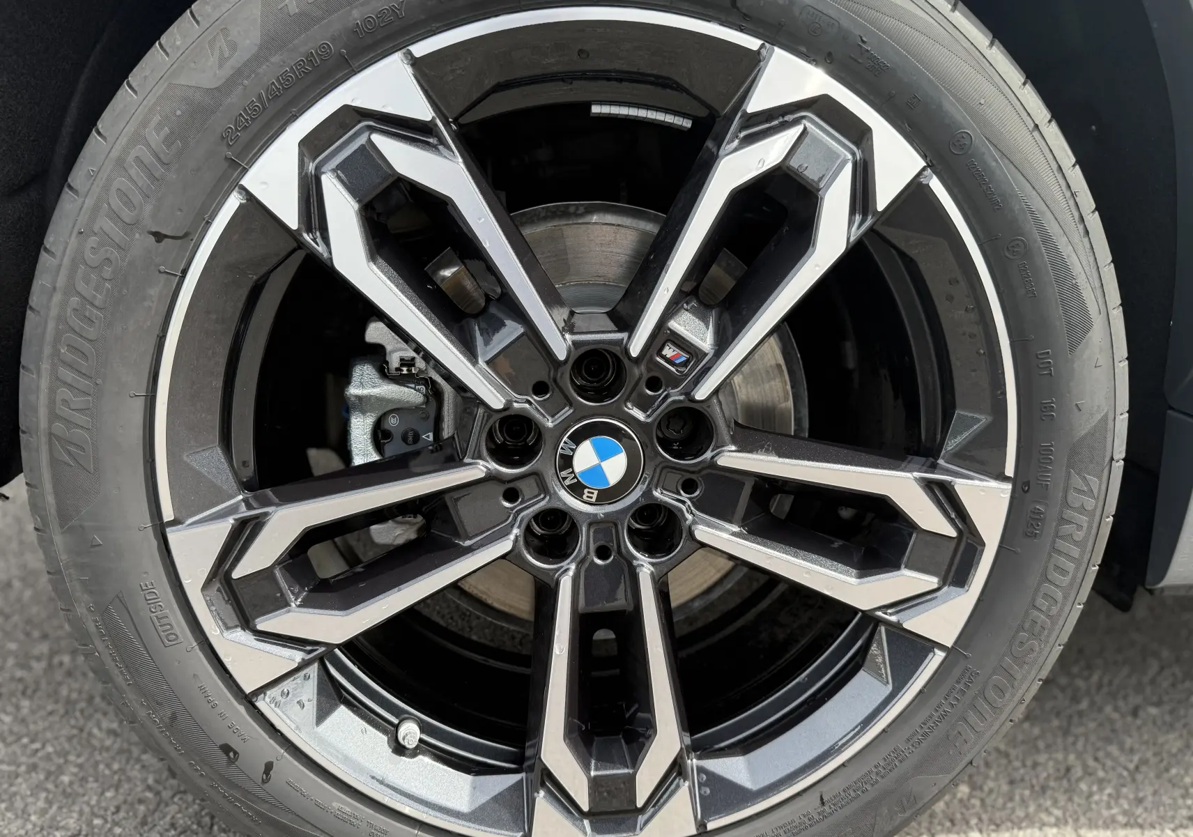 Gros plan sur la jante alliage 19 pouces bicolore d'une BMW X2 Skyscraper, mettant en valeur le logo M Sport central.