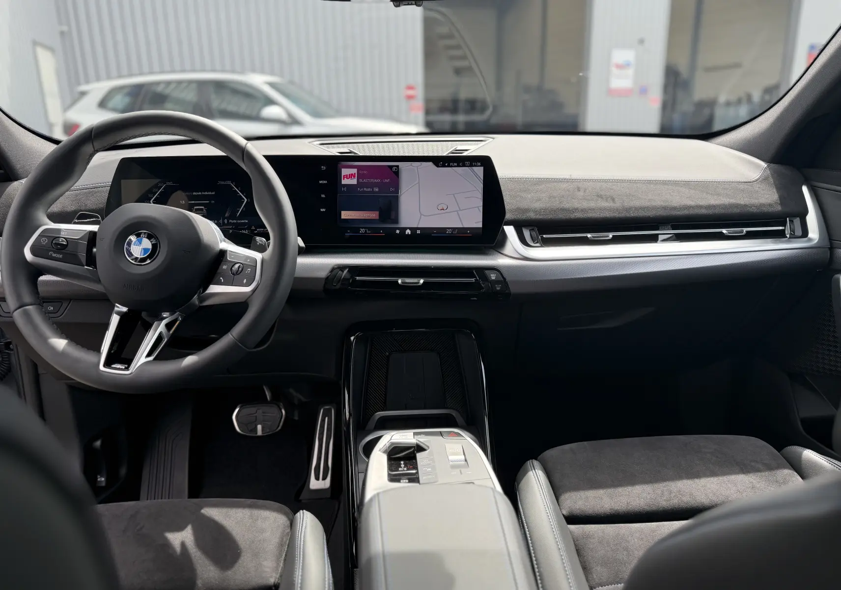 Vue intérieure avant du BMW X2 2025 en Skyscraper Grey, mettant en valeur le tableau de bord digital et le volant multifonction.