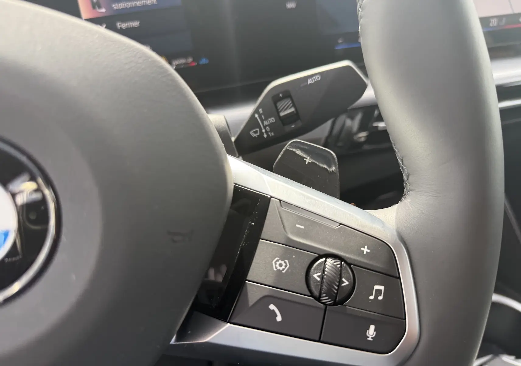 Gros plan sur les commandes au volant côté droit d’un BMW X2 2025, finition Skyscraper, avec palettes de changement de vitesse.