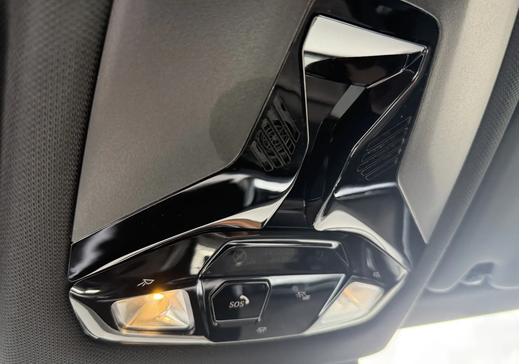 Vue intérieure en gros plan du plafonnier noir brillant avec commandes SOS et éclairage ambre dans une BMW X2 Skyscraper 2025.