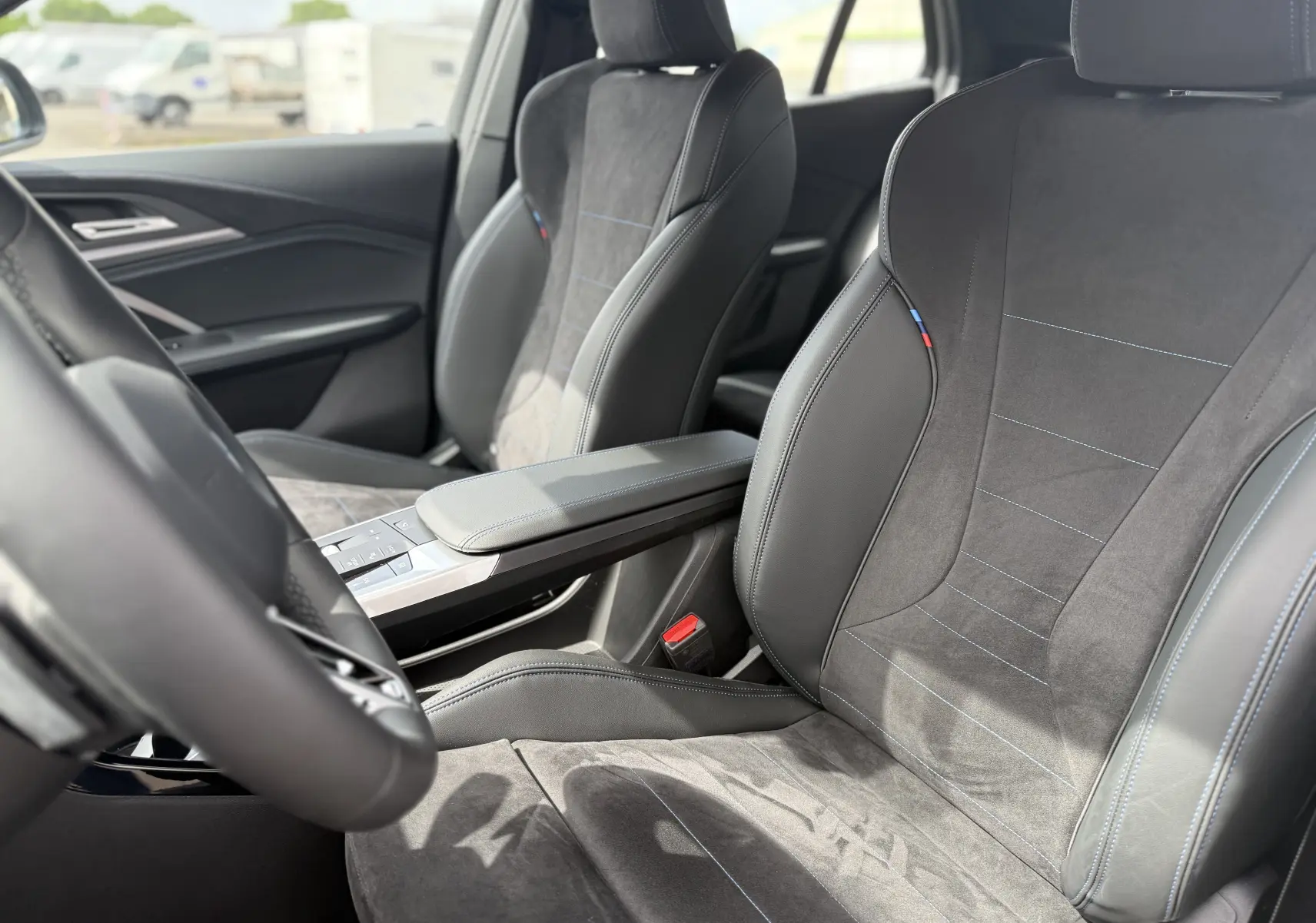 Vue intérieure rapprochée des sièges avant en cuir et alcantara gris avec surpiqûres bleues d’une BMW X2 2025.