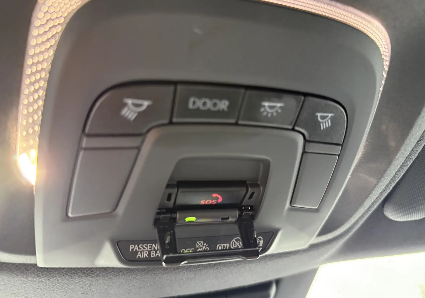Vue intérieure du plafonnier du Toyota C-HR hybride gris 2024, avec boutons d’éclairage et alerte SOS visible.