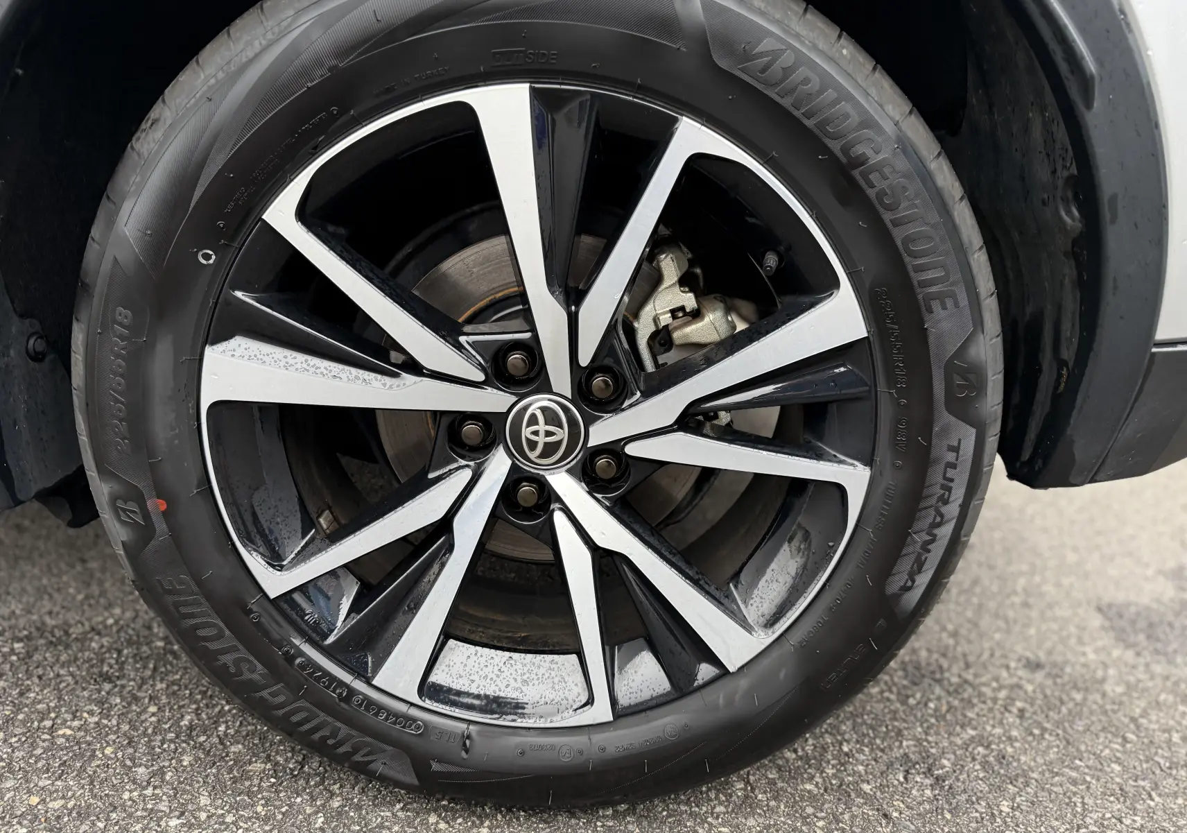 Gros plan sur la jante alliage bicolore noir et argent du Toyota C-HR Hybride gris, roue avant droite.