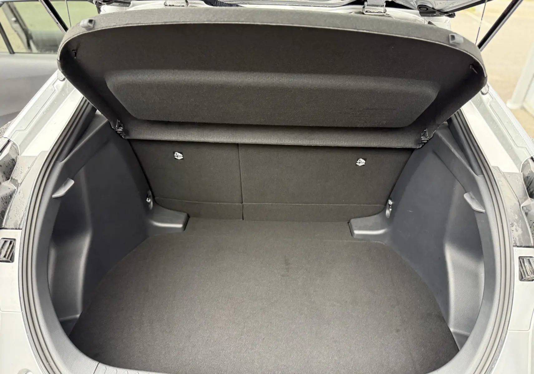 Coffre ouvert en vue plongeante du Toyota C-HR Hybride gris 2024, montrant un espace de chargement propre et spacieux.