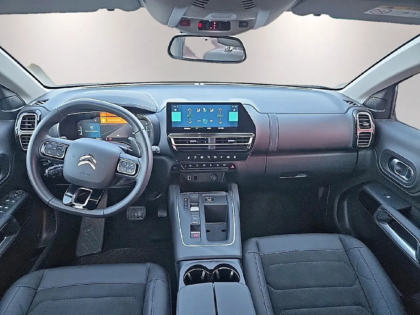 Vue intérieure avant du Citroën C5 Aircross 2024, tableau de bord et volant multifonction en cuir noir.