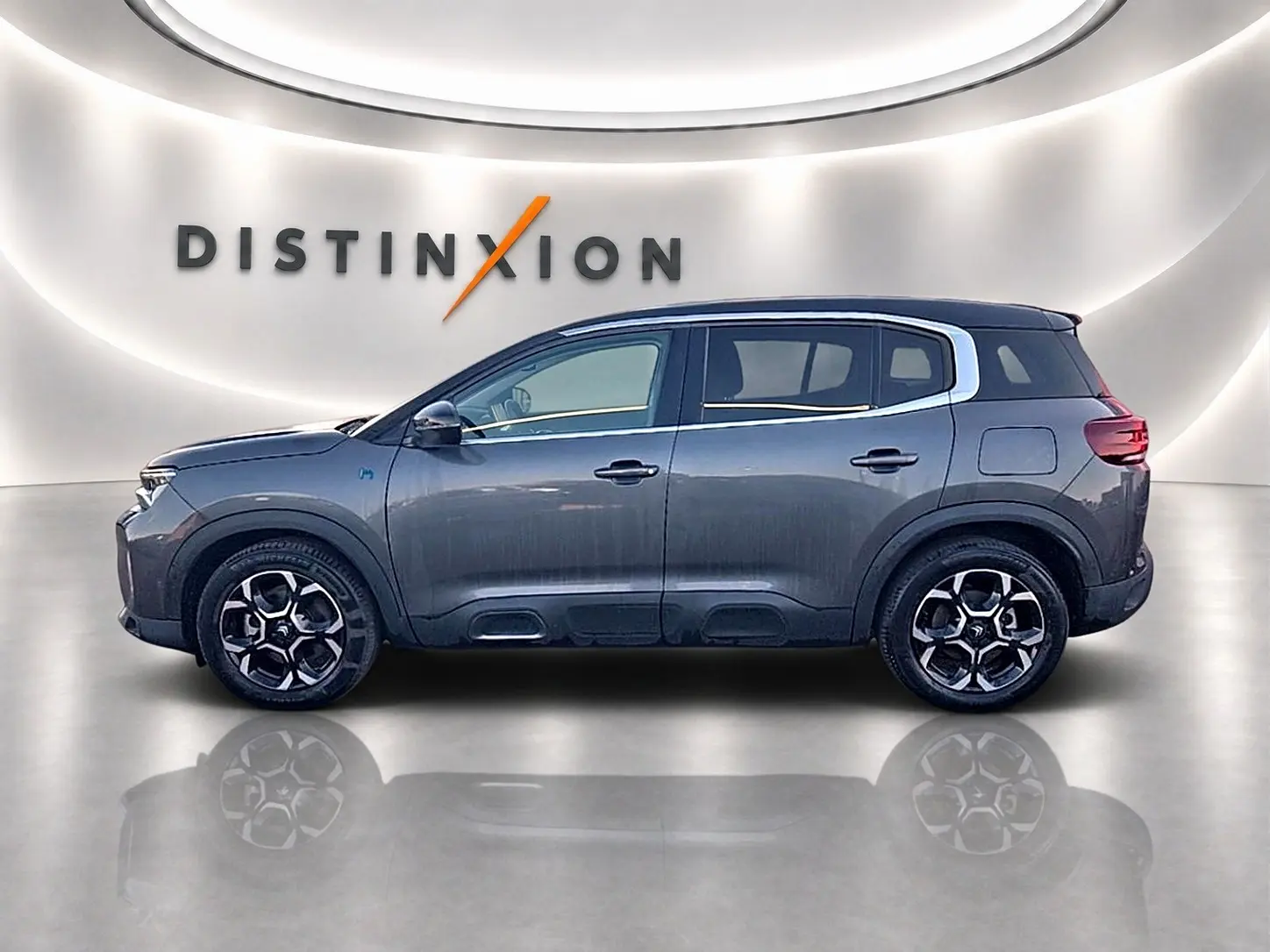 Profil côté gauche du Citroën C5 Aircross hybride gris platinium avec jantes alu et barres de toit visibles.