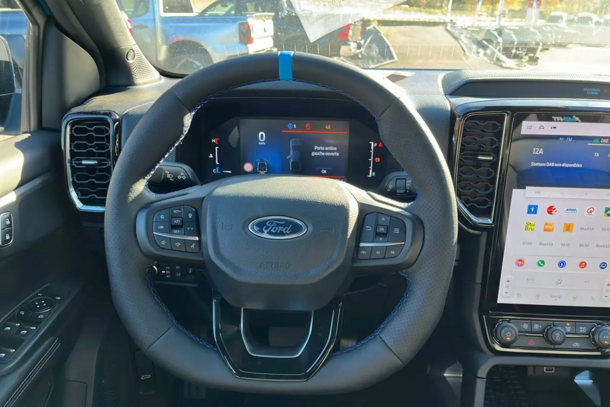 Vue intérieure centrée sur le volant cuir noir avec surpiqûres bleues du Ford Ranger gris carbone 2026.