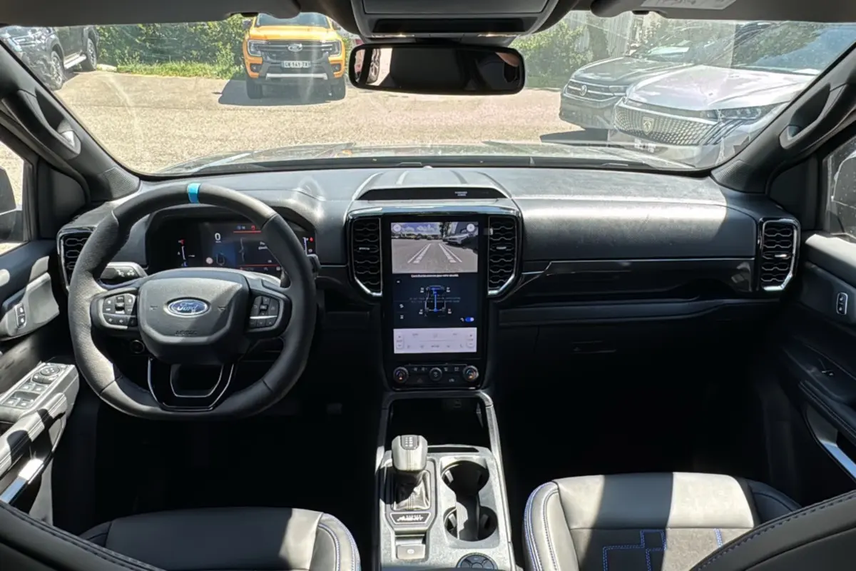 Vue intérieure avant du Ford Ranger gris carbone 2026, mettant en valeur le volant multifonctions et l'écran tactile central vertical.