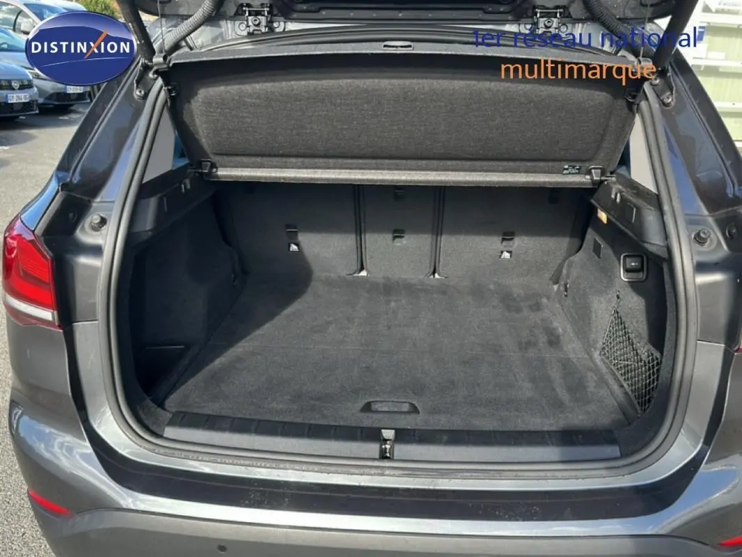 Coffre ouvert vu de l'arrière d'un BMW X1 gris foncé, montrant un espace de chargement propre et spacieux.