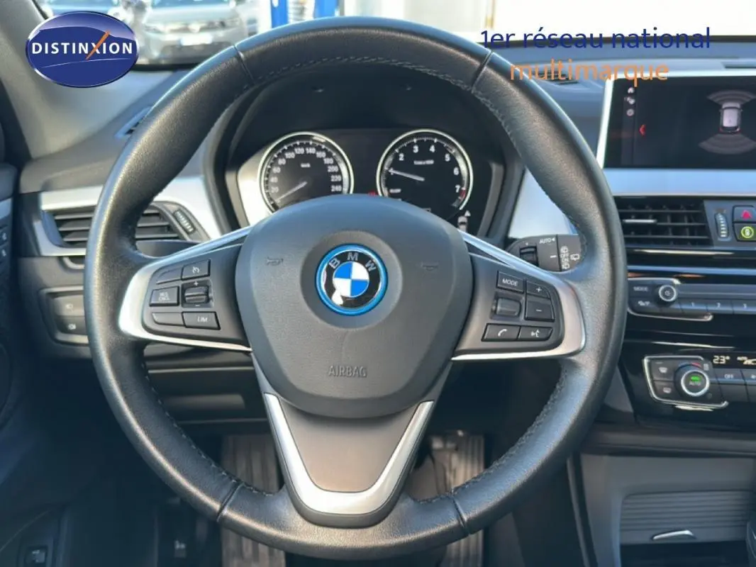 Vue centrée sur le volant sport noir de la BMW X1 2022 avec tableau de bord et écran multimédia visibles.