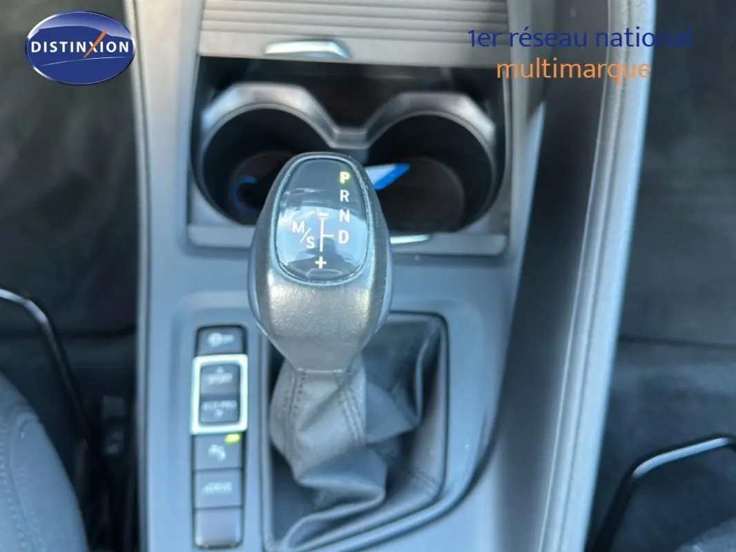 Gros plan sur le levier de vitesses automatique noir de la BMW X1 gris foncé, avec porte-gobelets en arrière-plan.