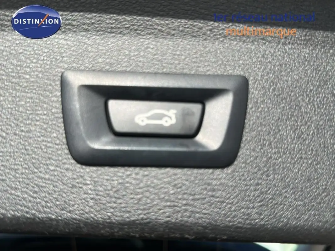 Bouton d'ouverture du coffre sur panneau intérieur d'un BMW X1 F48 LCI gris foncé, vue rapprochée.