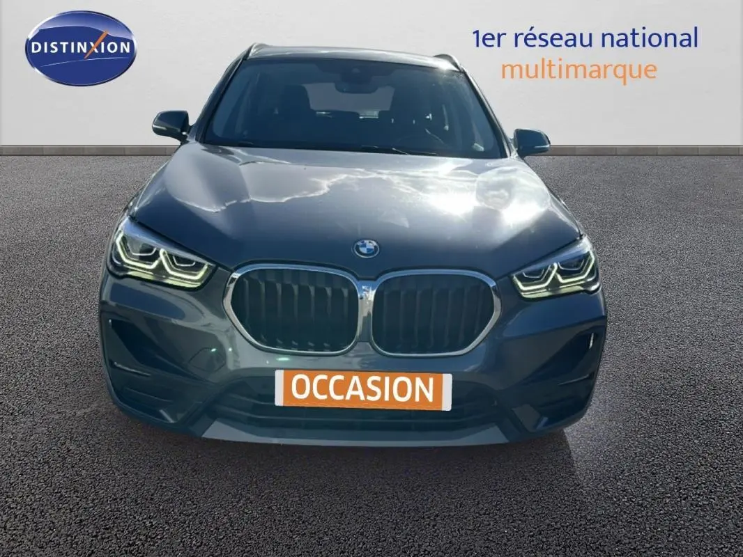 BMW X1 gris foncé vue de face avec calandre double et phares LED allumés sur fond neutre.