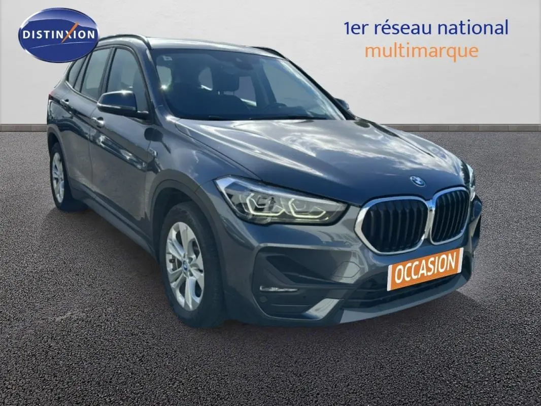 BMW X1 gris foncé vue 3/4 avant droit, avec calandre double haricot et jantes alliage 18 pouces visibles.