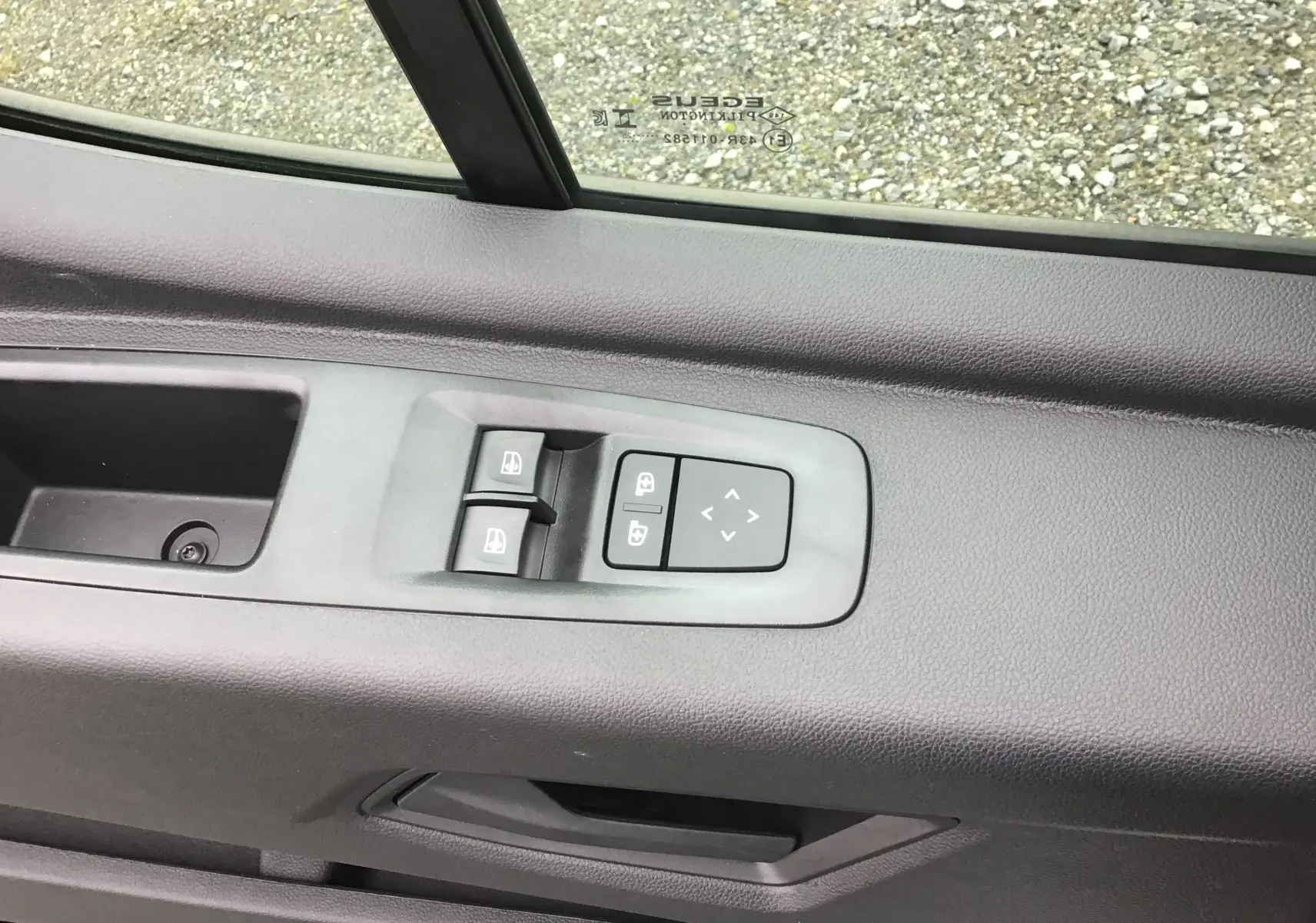 Détail des commandes de lève-vitres et réglage des rétroviseurs sur la porte côté conducteur du Renault Master blanc.