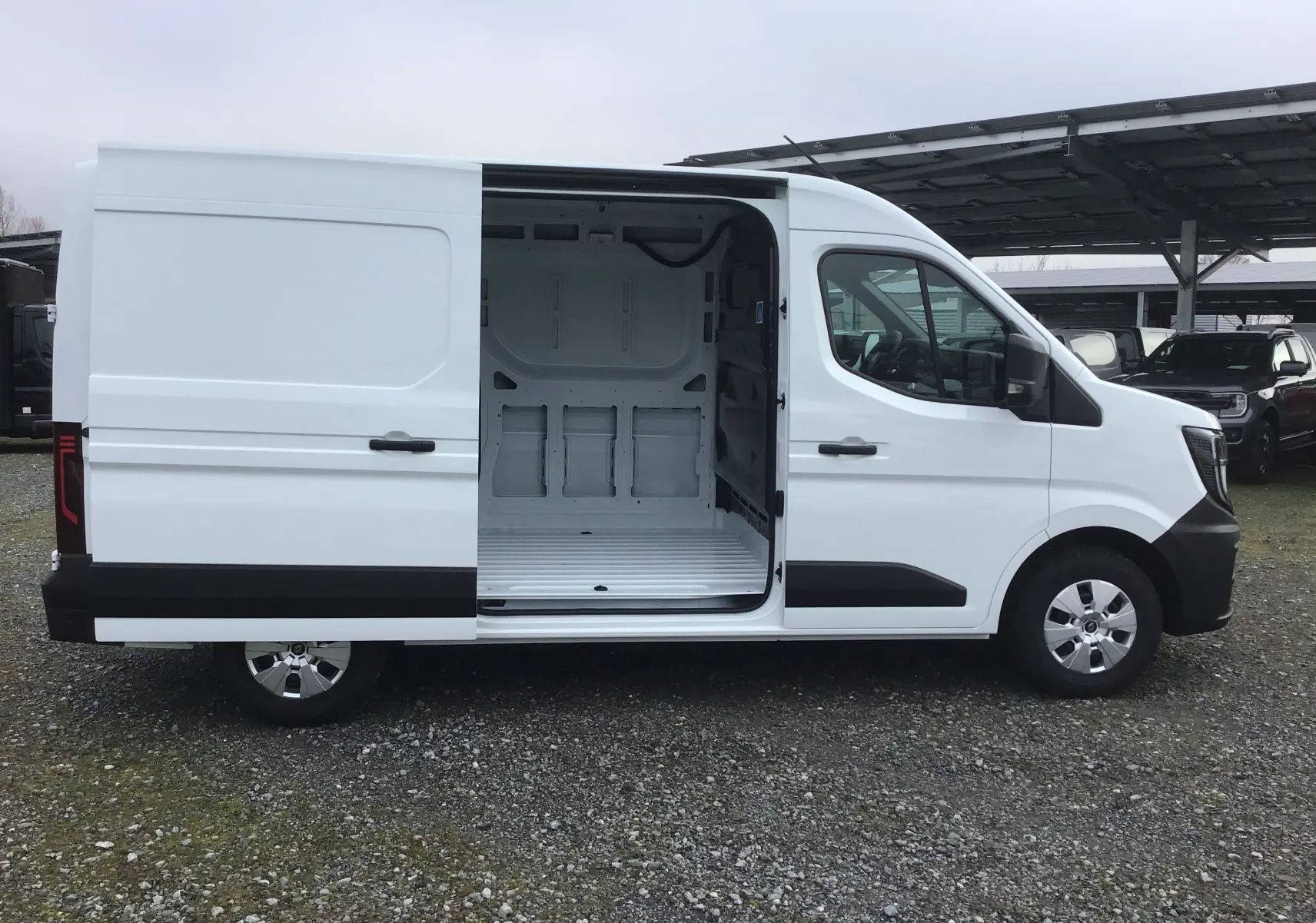 Vue latérale droite du Renault Master blanc 2025 avec porte coulissante ouverte montrant l’intérieur vide du fourgon.