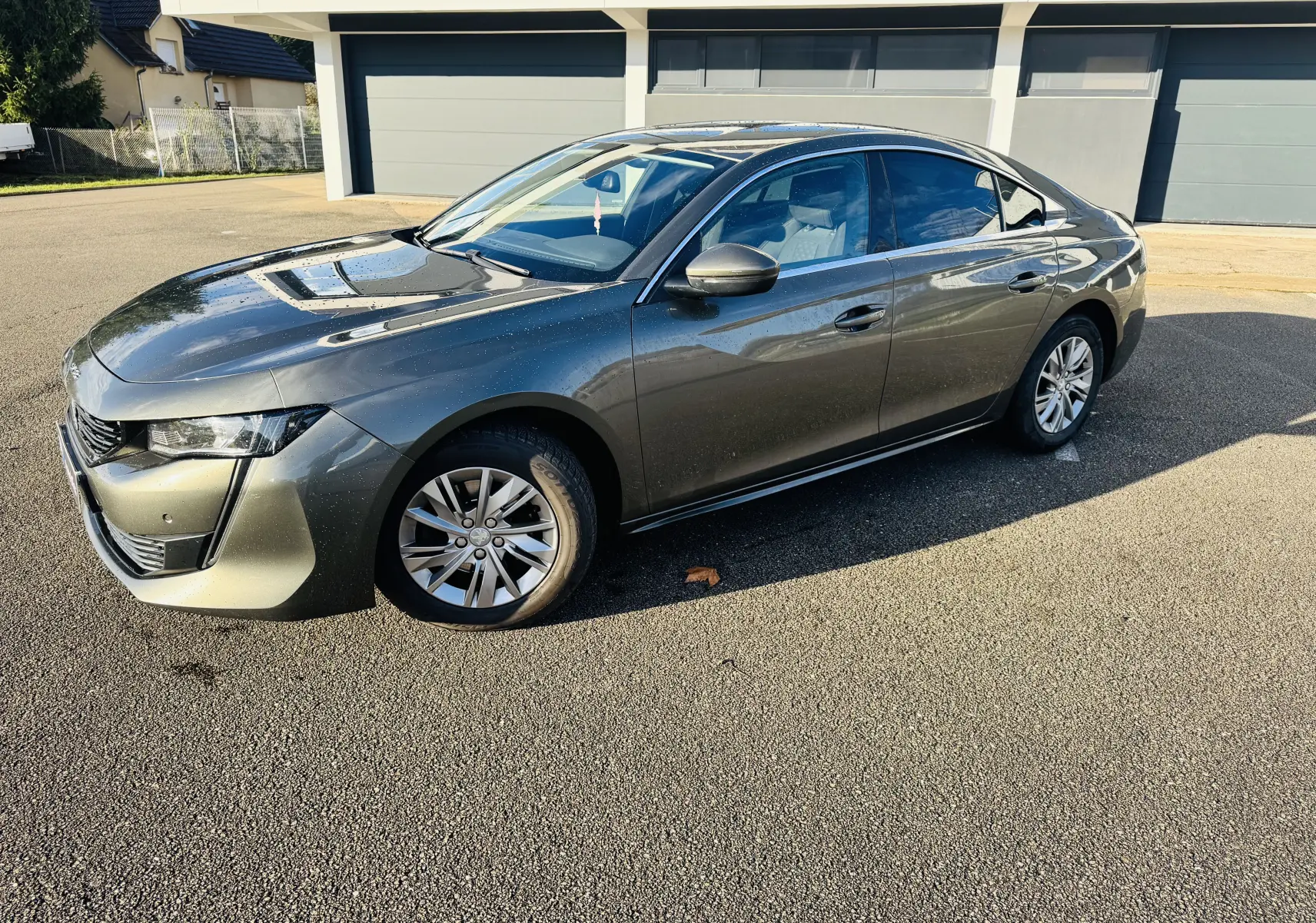 Peugeot 508 gris amazonite vue 3/4 avant droit sur parking, avec jantes alliage et calandre chromée.