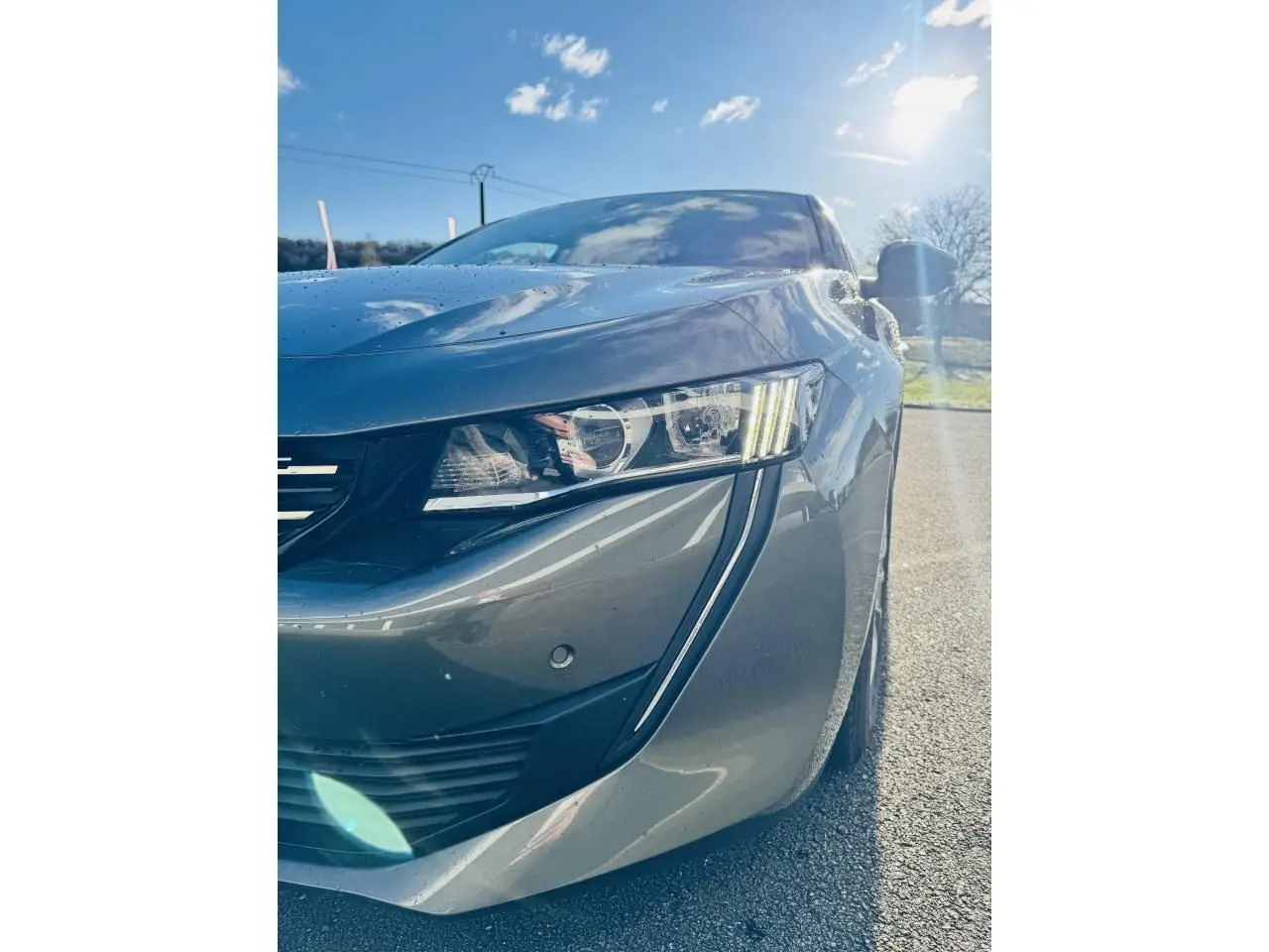 Gros plan sur l'avant droit gris amazonite d'une Peugeot 508 2019, mettant en valeur le phare et la calandre chromée.